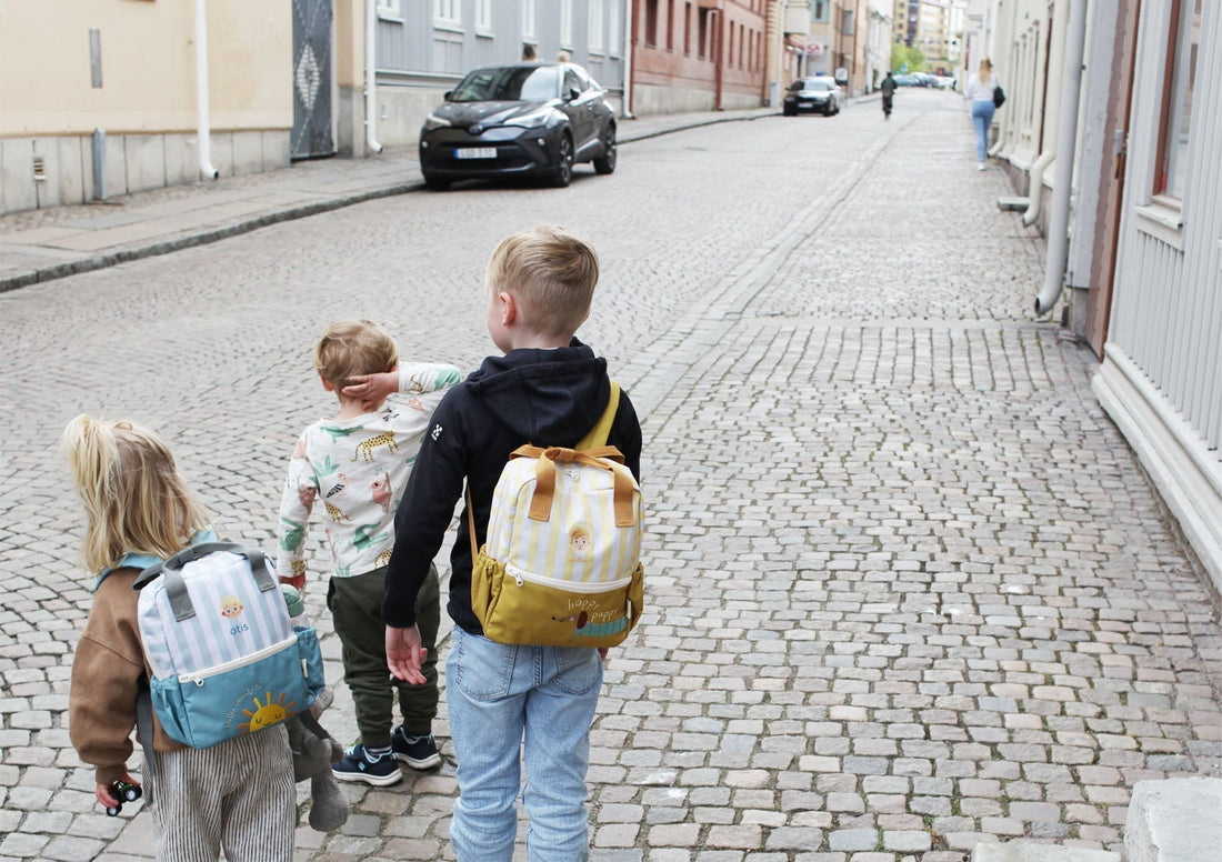Tre barn med personliga ryggsäckar på väg till förskolan